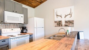 A kitchen with a wooden countertop, a stove, a coffee maker, a refrigerator, and a sink. - Cottage at the Creek ~ On S. Sylamore (Mountain View)