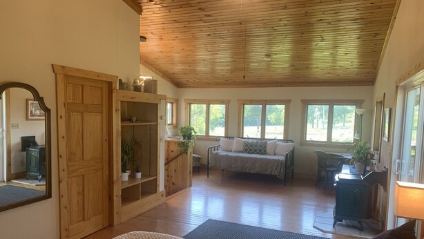 A spacious room with a large bed, wooden ceiling, and a cozy seating area with a sofa and a table. - The Dairy at the Wegmueller Farm - stay on a Wisconsin farm! (Monroe)