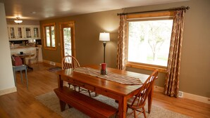 A dining area with a wooden table, benches, and chairs, a lamp, and a view of the outdoors through a window. - The Dairy at the Wegmueller Farm - stay on a Wisconsin farm! (Monroe)