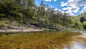 A river with clear water, surrounded by trees and rocky terrain. - Cabin-ette at the Creek ~ a Tiny Ozark Getaway (Mountain View)