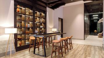 Een modern interieur met een houten bar, barkrukken, een grote boekenkast en een vloer met een patroon.