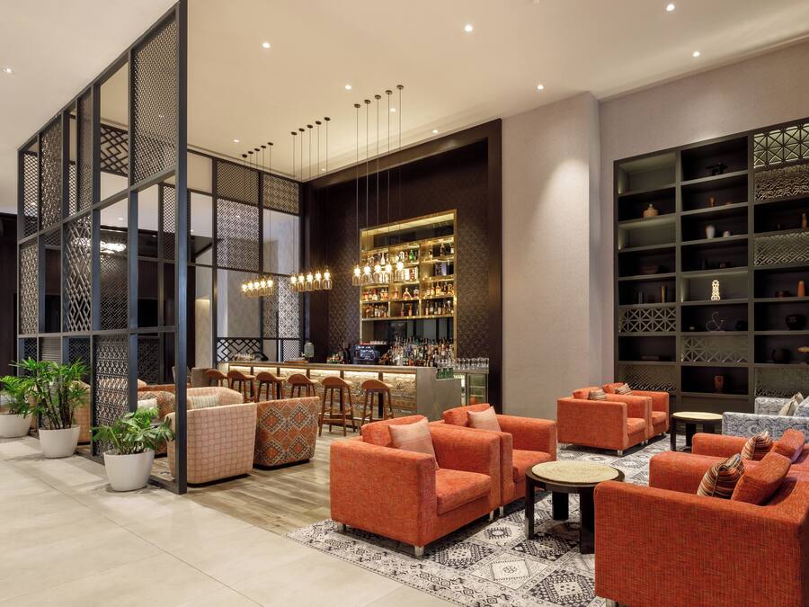 Un espace détente moderne avec des canapés orange, un bar doté d’une vitrine et des étagères décoratives.
