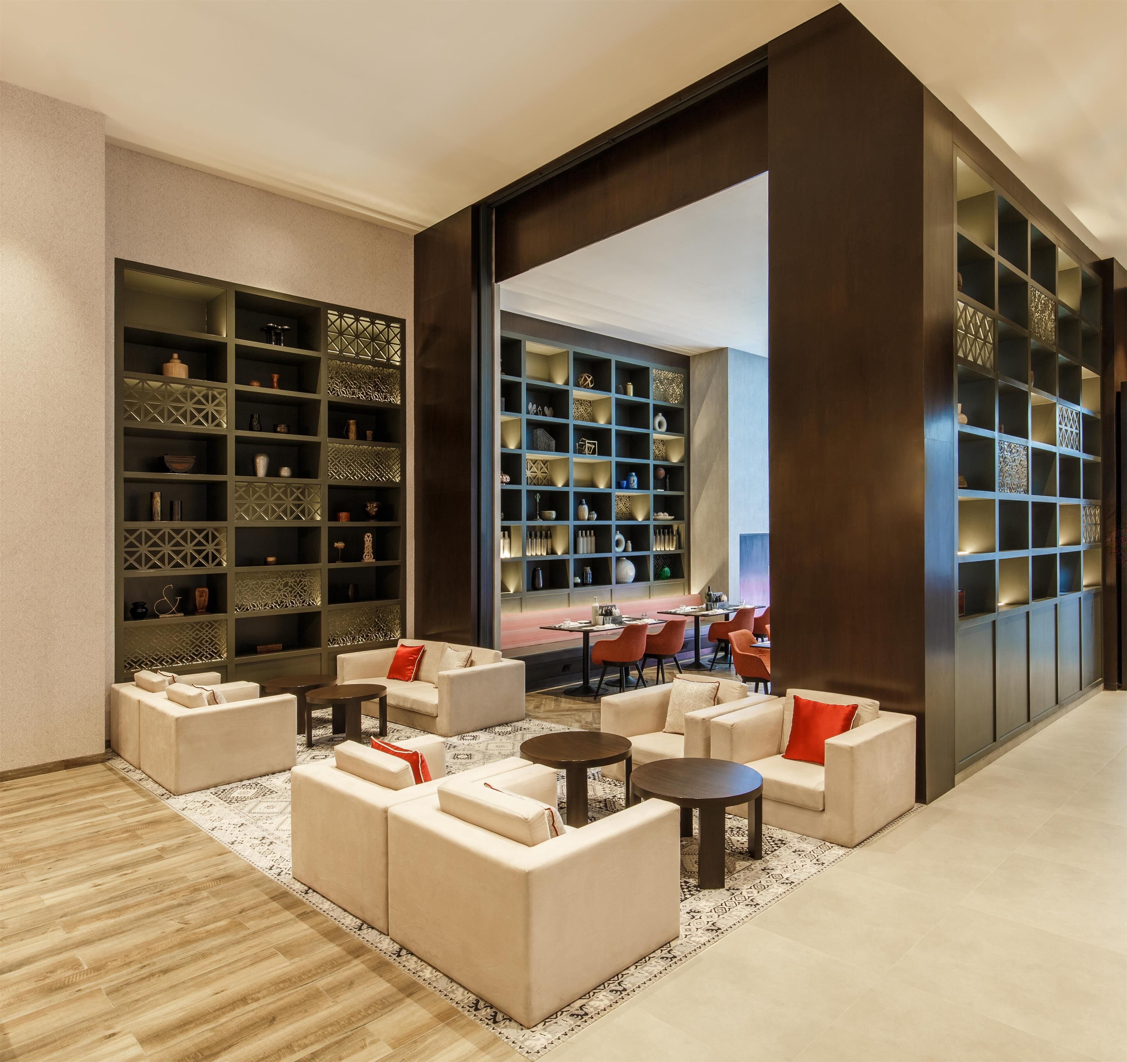 A modern lounge area with sofas, tables, and a large bookshelf filled with decorative items.