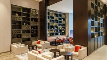 A modern lounge area with sofas, tables, and a large bookshelf filled with decorative items.