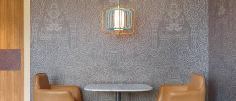 A room with a round table, two leather chairs, a patterned wall, and a hanging light fixture.