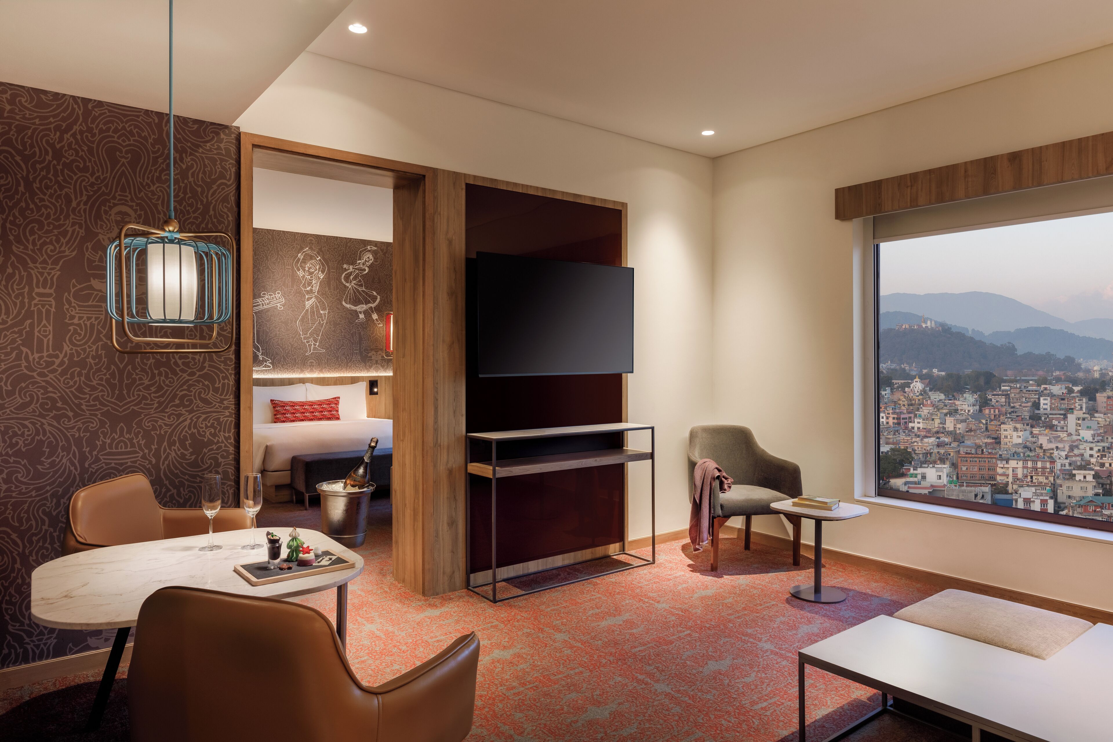 Ein modernes Hotelzimmer mit Blick auf die Stadt, einem Flachbildfernseher, einem Essbereich und einer gemütlichen Sitzecke.
