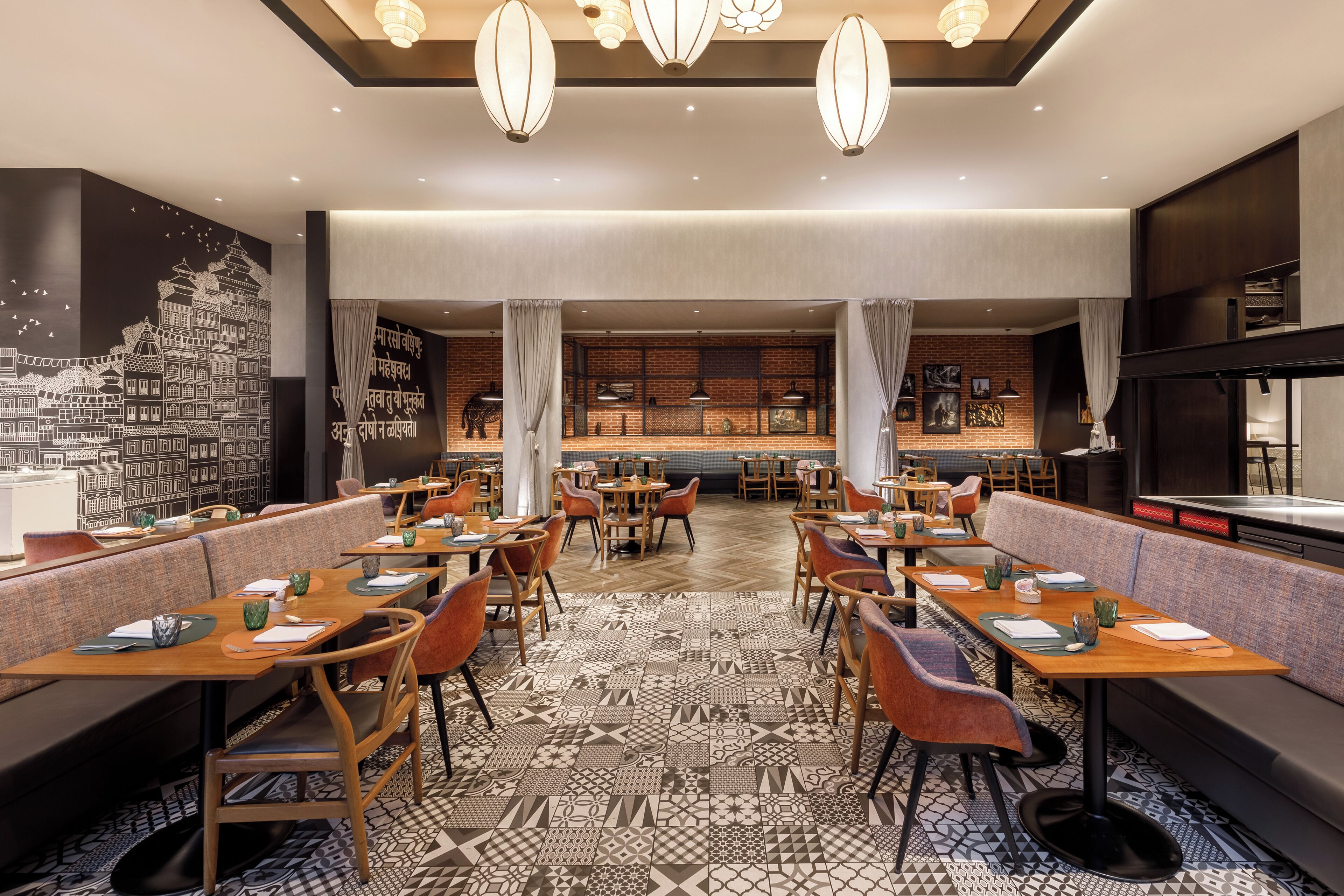 Un restaurante con varias mesas y cabinas, suelo estampado y lámparas colgantes.