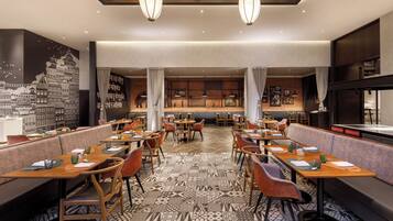 Un restaurante con varias mesas y cabinas, suelo estampado y lámparas colgantes.