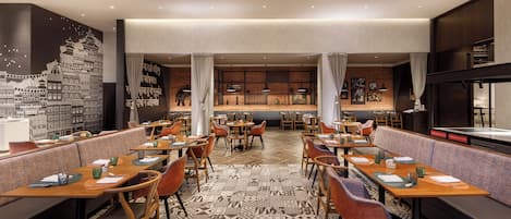 A restaurant with multiple tables and booths, a patterned floor, and hanging light fixtures.