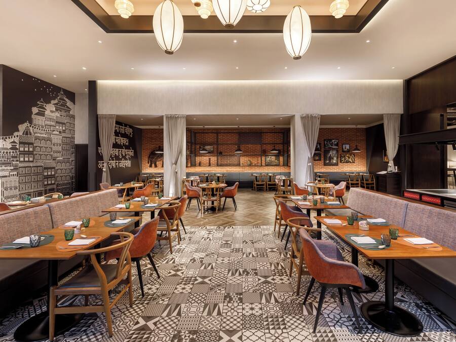 Un restaurante con varias mesas y cabinas, suelo estampado y lámparas colgantes.