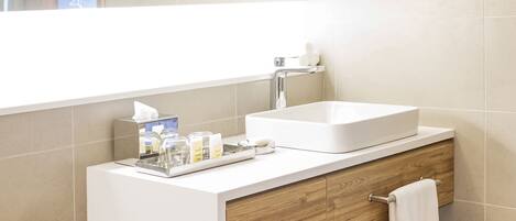 Un baño moderno con lavabo blanco, tocador de madera y un espejo grande.