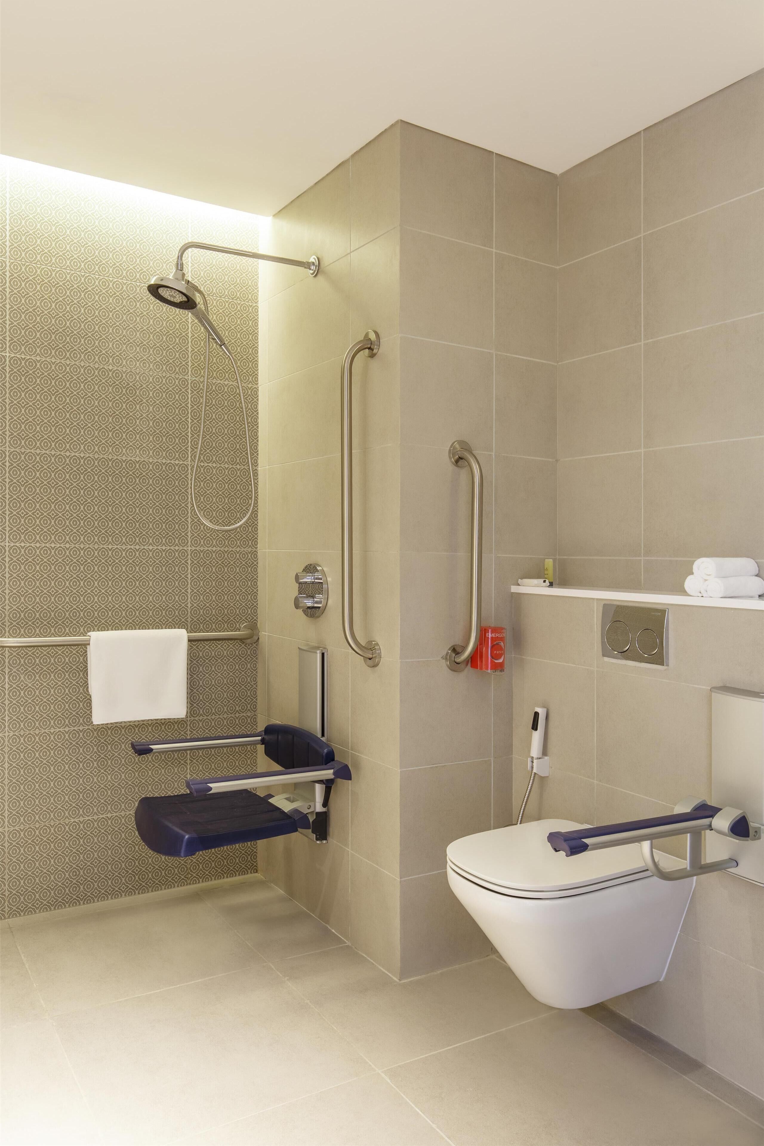 A modern bathroom with a shower, toilet, and grab bars.