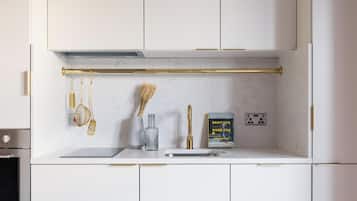 A modern kitchen with white cabinets, a marble backsplash, a gold faucet, and a cookbook on the counter.