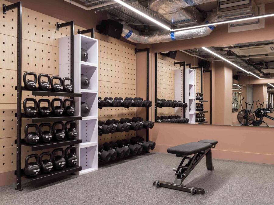A gym with weight racks, a bench, and a mirror.