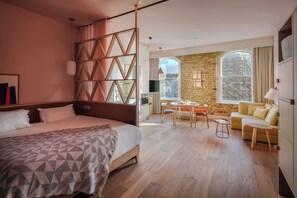 A hotel room with a large bed, a dining area, a sofa, and a stone wall. - Zanzibar Locke (Dublin)