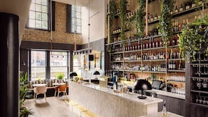 Un espace bar avec un long comptoir, des sièges et des étagères remplies de bouteilles.