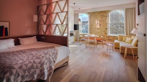 A hotel room with a large bed, a dining area, a sofa, and a stone wall. - Zanzibar Locke (Dublin)