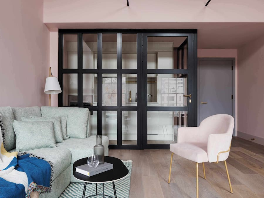 A modern living room with a sofa, a coffee table, a chair, and a large sliding glass door leading to a kitchen.