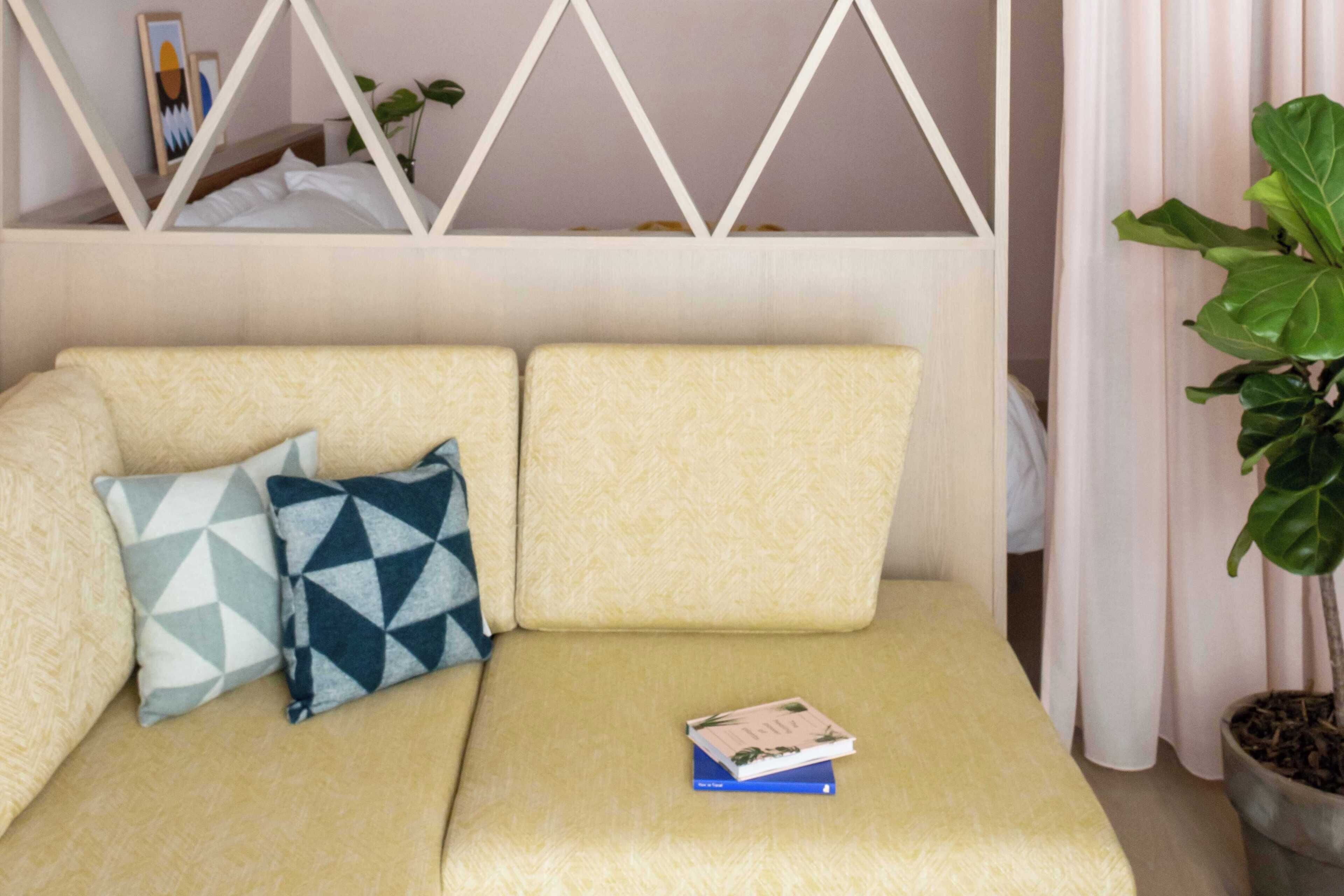 A sofa with patterned cushions, a book, and a potted plant.
