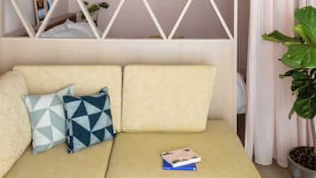 A sofa with patterned cushions, a book, and a potted plant.