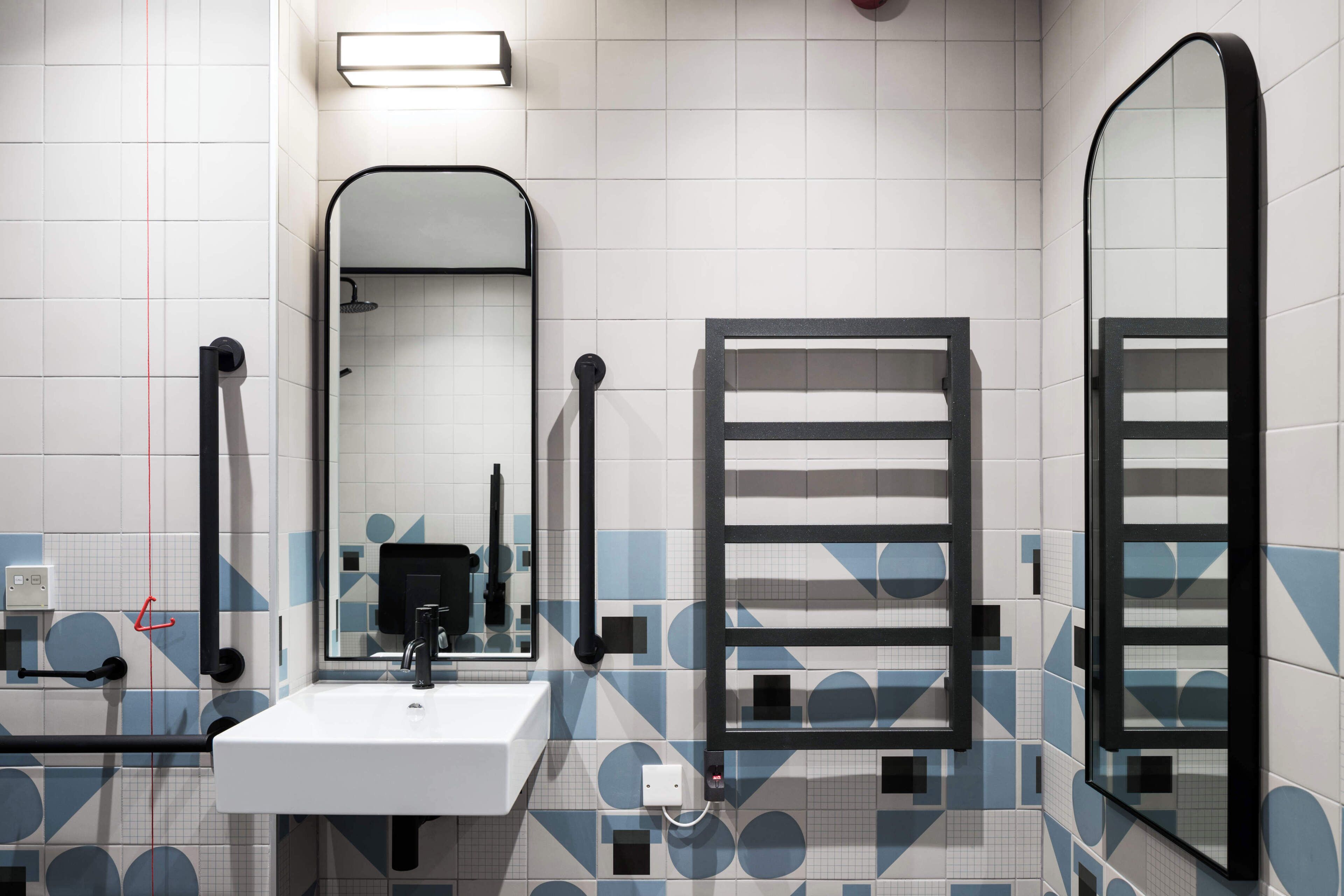 A bathroom with a white sink, a mirror, a towel rack, and a shower area.