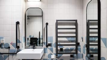 A bathroom with a white sink, a mirror, a towel rack, and a shower area.