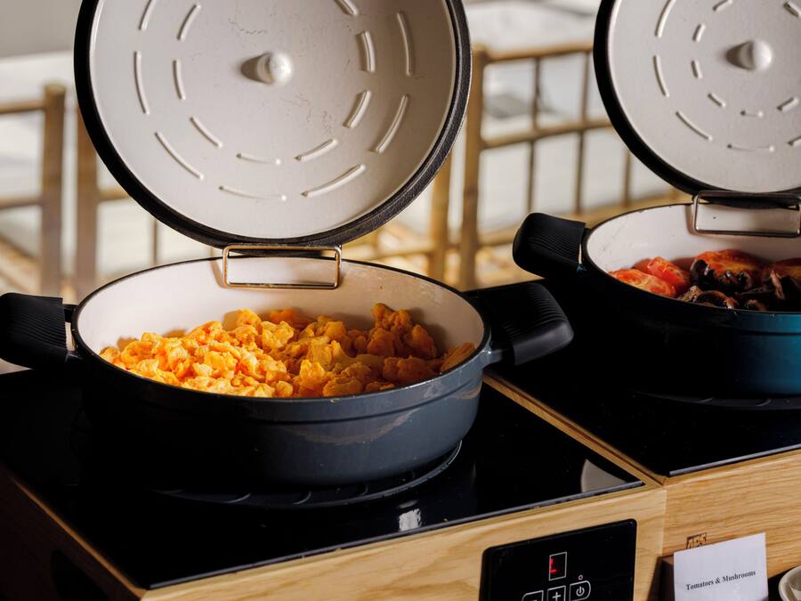 Two electric skillets on a stove with a control panel and a sign indicating 'Tomatoes & Mushrooms.'