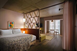 A hotel room with a bed, a seating area with a table and chairs, and a view through a partition. - Zanzibar Locke (Dublin)