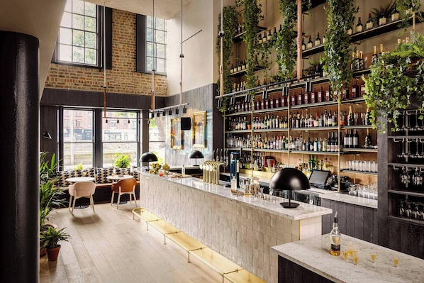 Eine Bar mit Sitzgelegenheiten, Flaschenregalen und Blick auf die Straße.