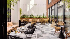 A modern outdoor seating area with wicker furniture, a sofa, and tables. - Zanzibar Locke (Dublin)