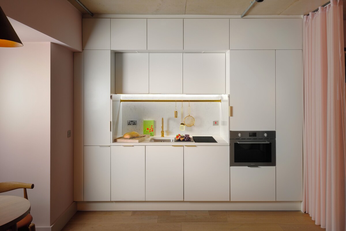 A modern kitchen with white cabinets, a built-in oven, and a countertop with a sink.