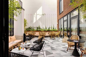 A modern outdoor seating area with wicker furniture, a sofa, and a table with drinks. - Zanzibar Locke (Dublin)