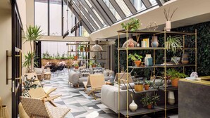 A spacious lounge area with a checkered floor, seating arrangements, and a variety of potted plants. - Zanzibar Locke (Dublin)
