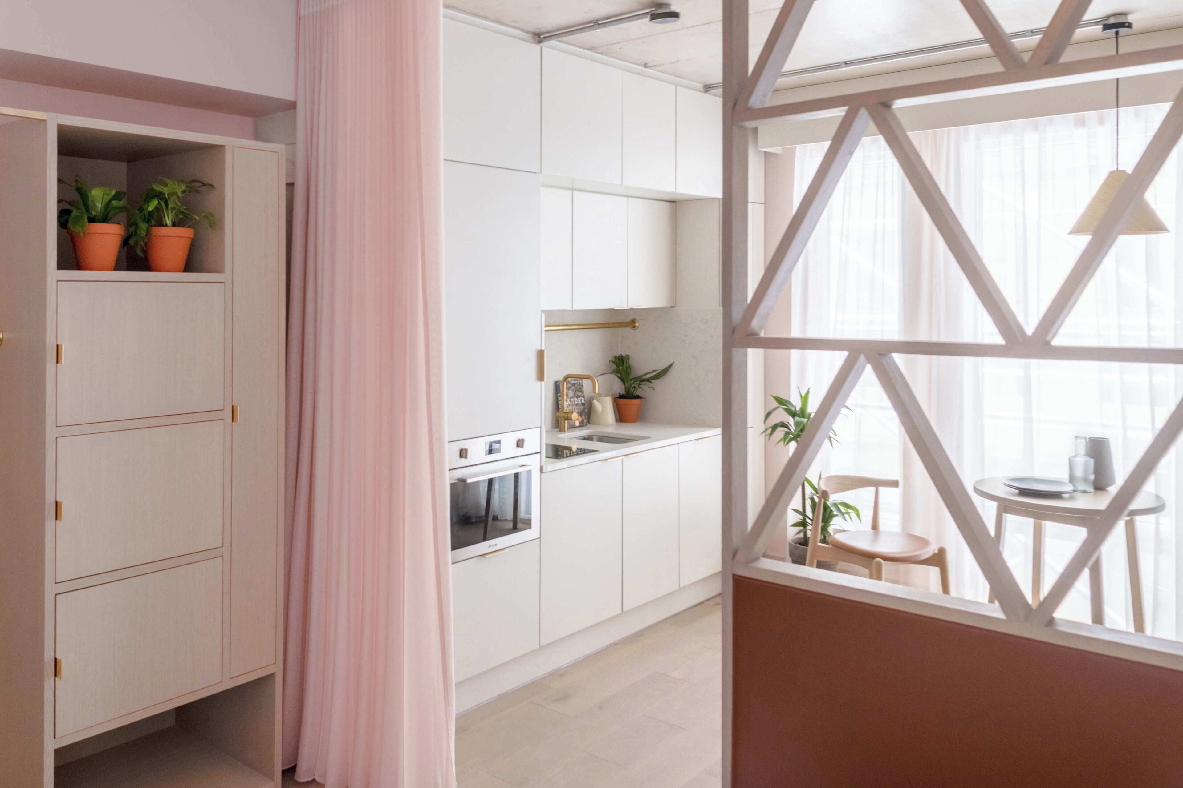 Une cuisine moderne avec des meubles blancs, une cuisinière et un coin repas comprenant une table et des chaises.