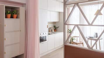 Een moderne keuken met witte kasten, een fornuis en een eethoek met een tafel en stoelen.