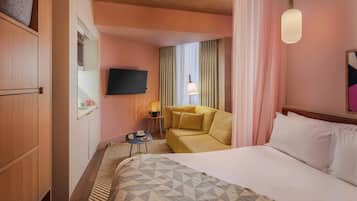 A hotel room with a bed, a sofa, a television, a lamp, and a small table.