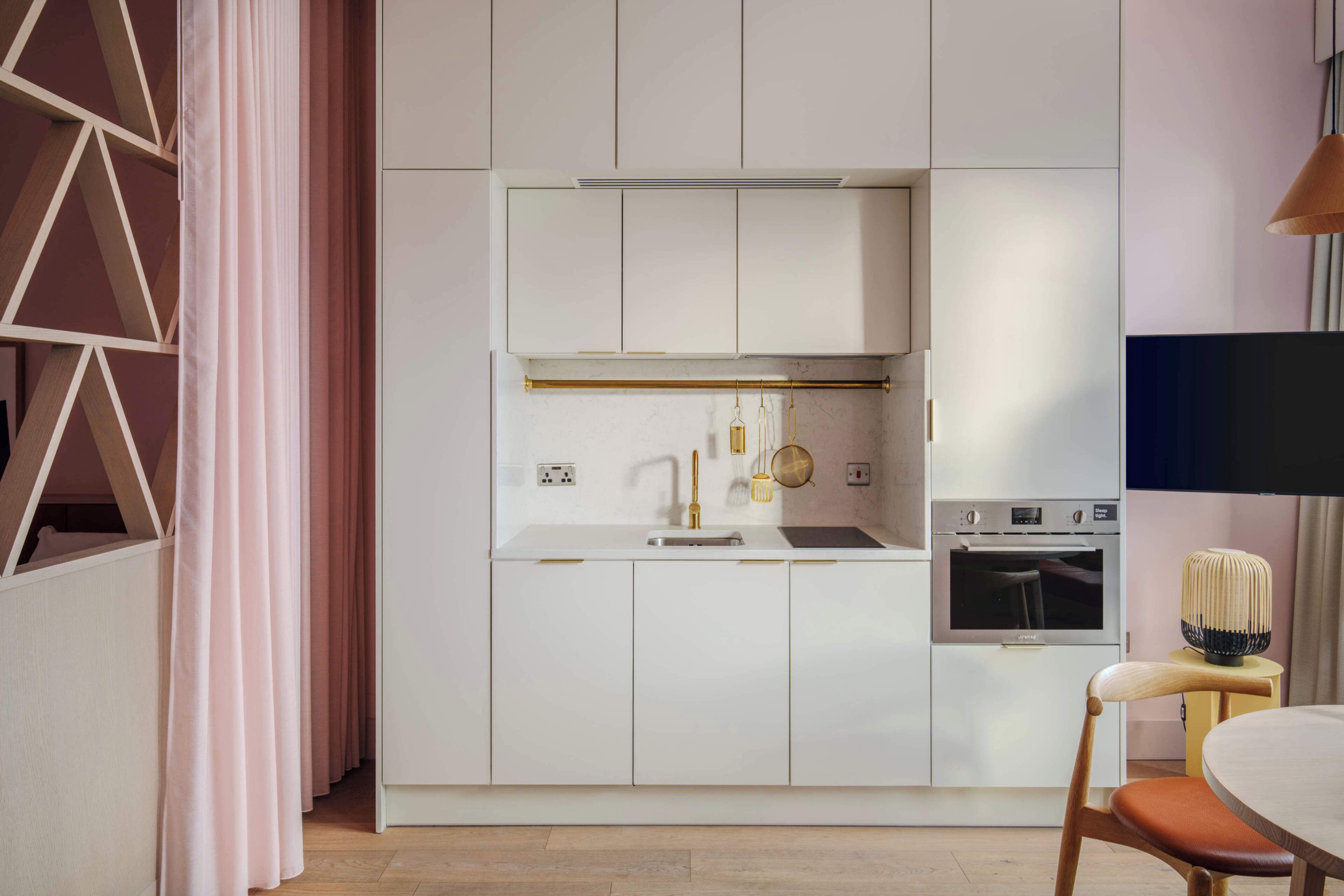 Eine moderne Küche mit weißen Schränken, einem eingebauten Backofen und einer Pendelleuchte.