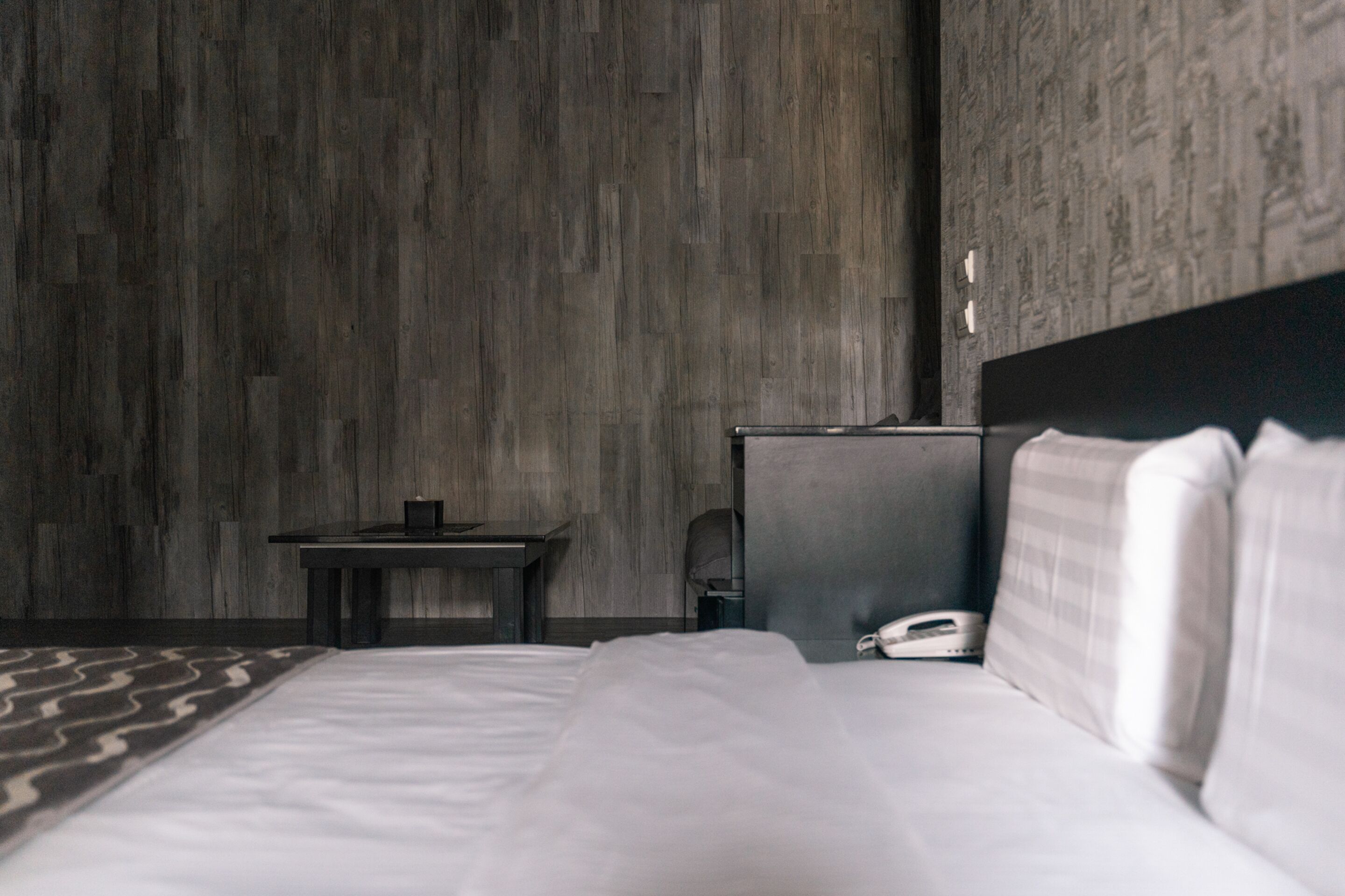 A hotel room with a large bed, a bedside table, a desk, and a telephone.
