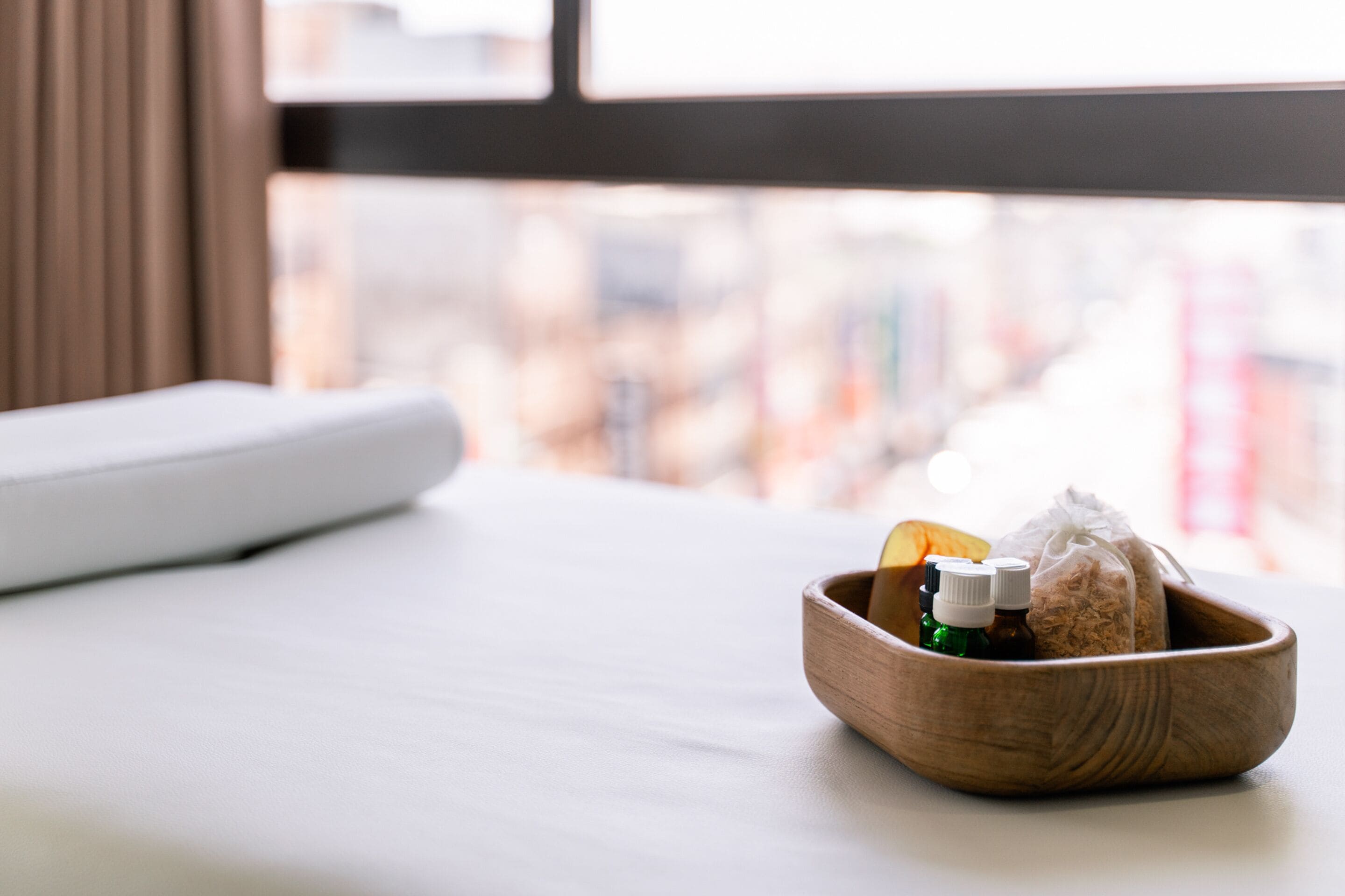 A wooden bowl on a white table with a window view.