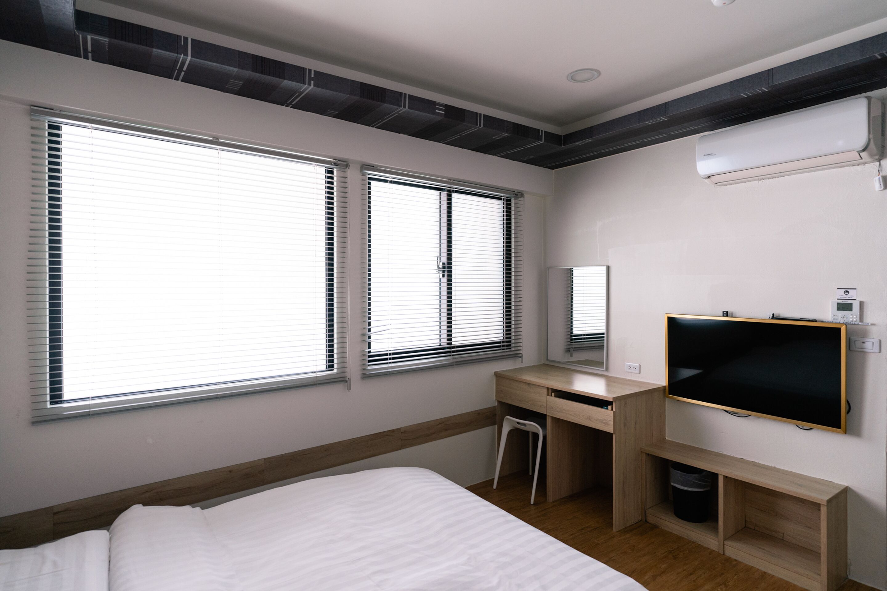 A modern hotel room with a large bed, a desk, and a TV.