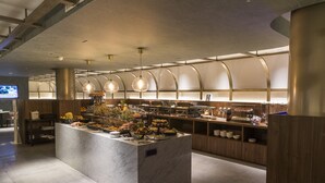 A modern kitchen area with a marble island, wooden cabinets, and a variety of food items. - Mercure St. Julian's Malta (St. Julian's)
