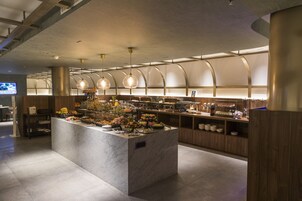 Un área de cocina moderna con una isla de mármol, armarios de madera y una variedad de alimentos.