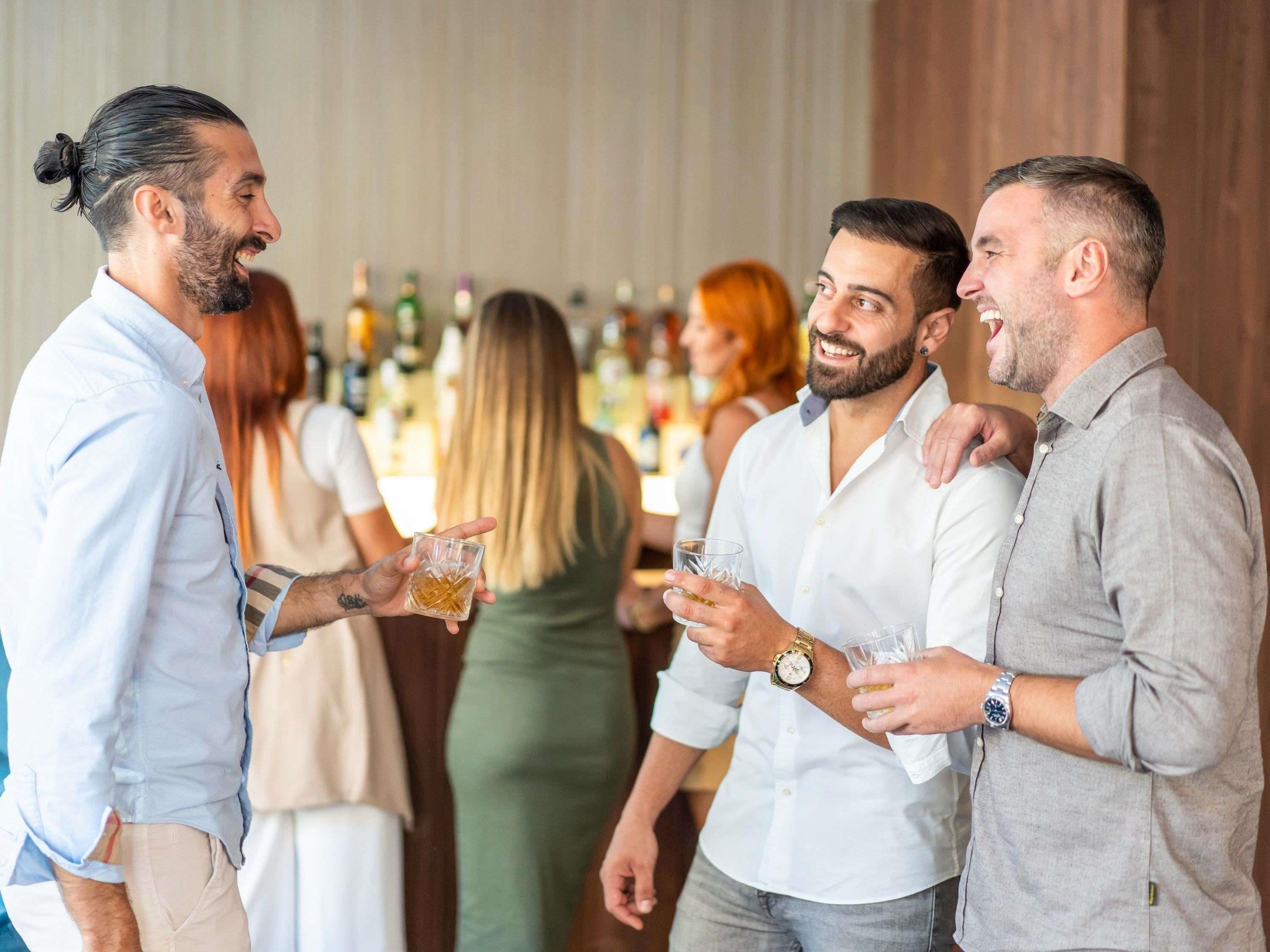 Un groupe de personnes est réuni dans un bar, avec des bouteilles en arrière-plan.