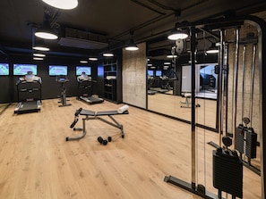 Une salle de sport équipée de tapis de course, d’un banc de développé couché et d’appareils de musculation.