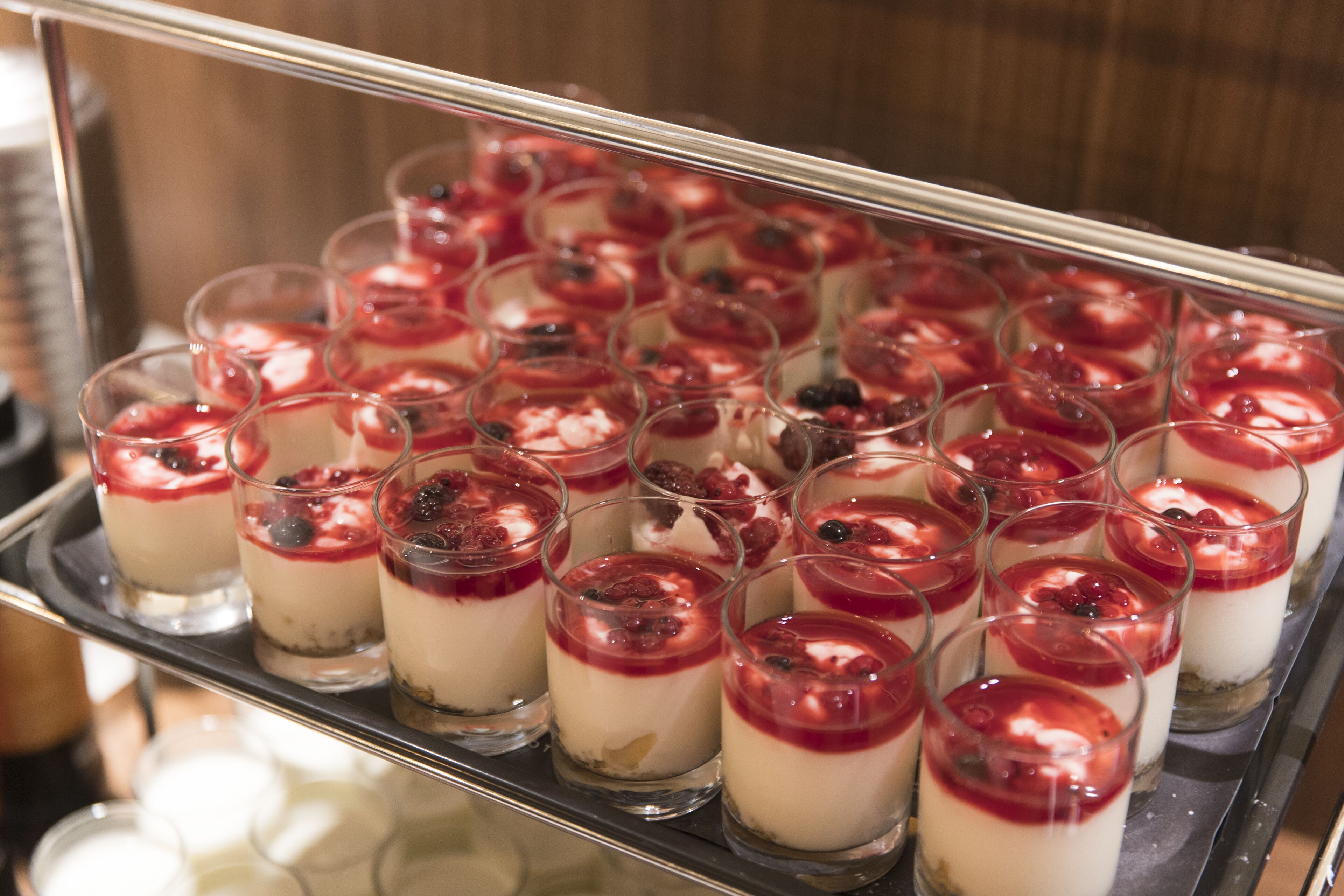 A tray of parfaits with a red fruit topping.