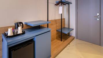 A modern hotel reception desk with a coffee machine, a tray with cups and a glass, and a wooden accent wall.