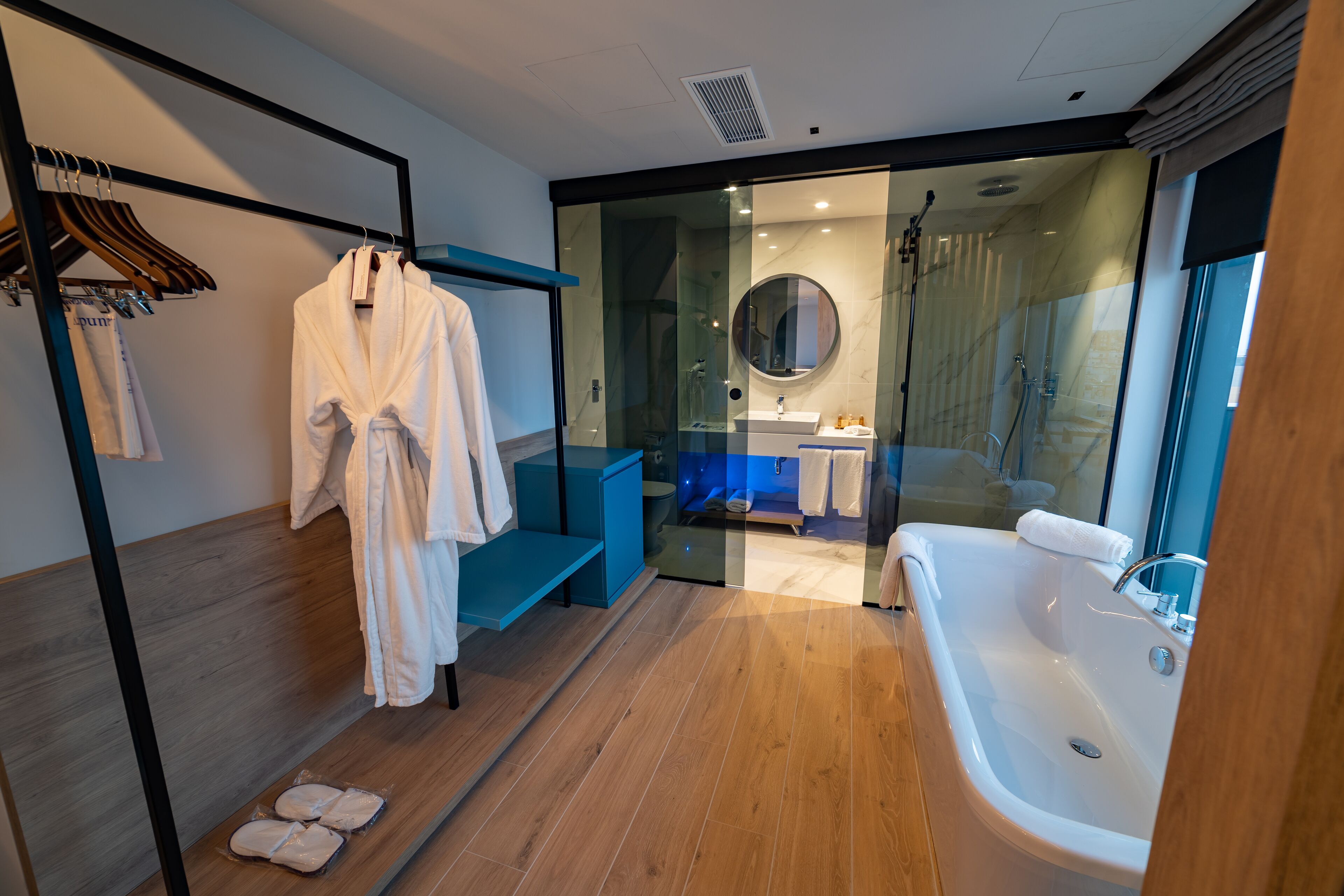 Une salle de bain moderne avec une douche à parois de verre, une grande baignoire et un banc en bois.
