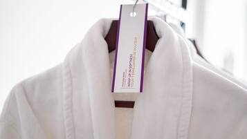 A white robe hanging on a rack with a tag that reads "PRIVATE CHAMBER WRAUP IN SOFTNESS POUR UP IN SOFTNESS."