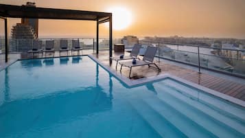 Una piscina al aire libre, sombrillas, tumbonas