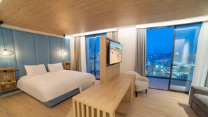 A modern hotel room with a large bed, a wooden desk, a TV, and a city view through the window. - Mercure St. Julian's Malta (St. Julian's)